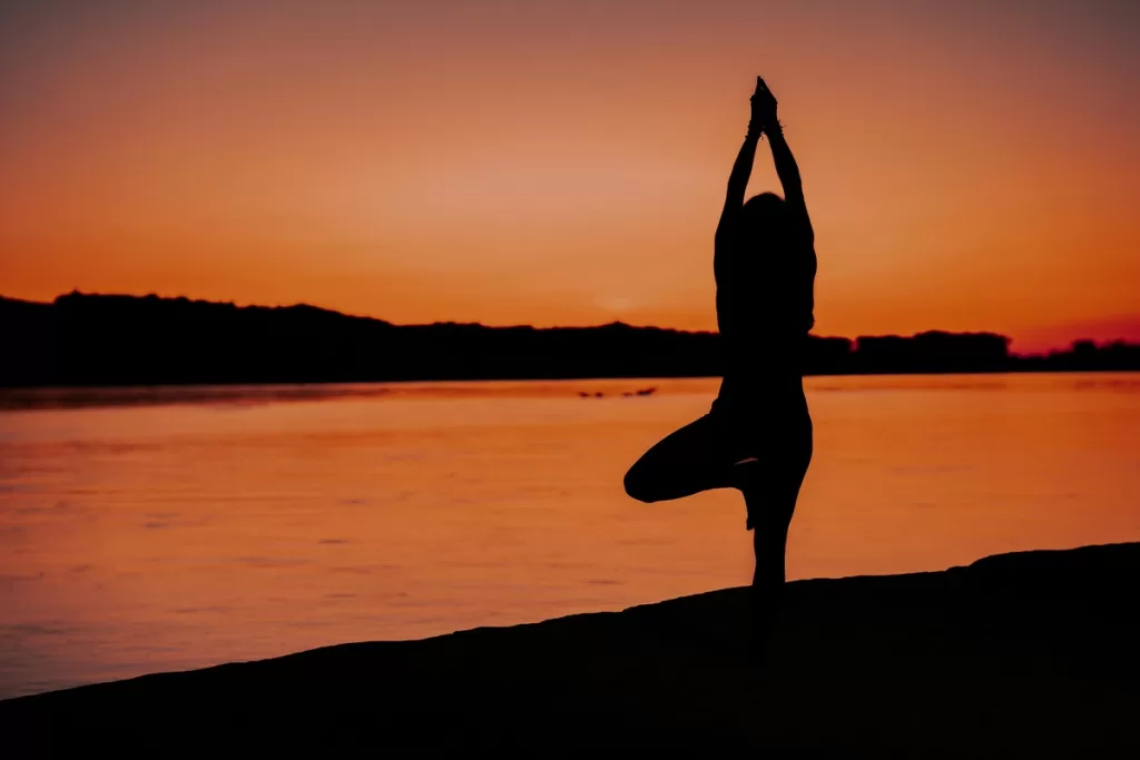 A silhueta de uma mulher ao pôr do sol praticando Ashtanga Yoga.